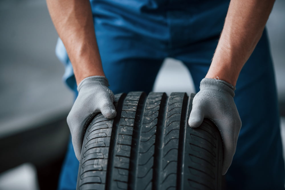 dirt wheel mechanic holding tire repair garage replacement winter summer tires